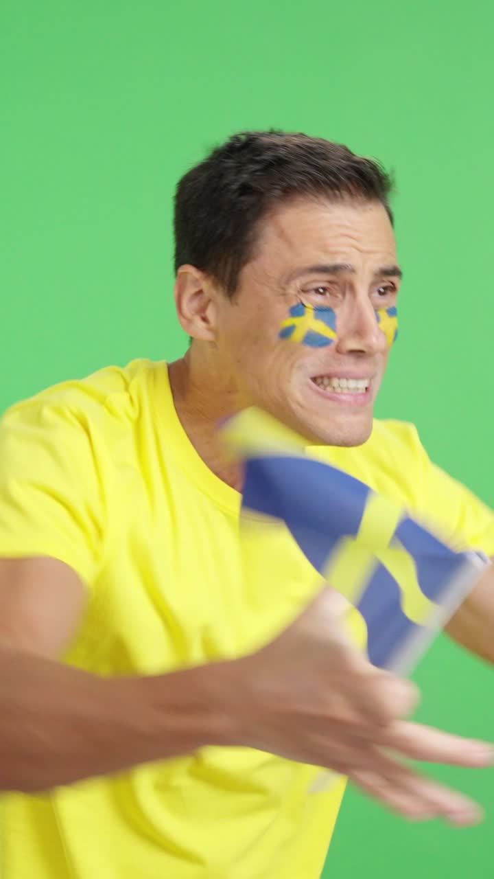 Uomo nervoso che esulta per la Svezia durante una partita, guardando da un'altra parte