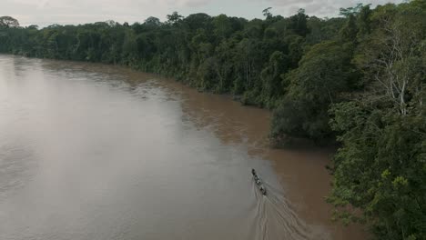 aerial view of travelling canoe across a river in the green jungle of ecuador