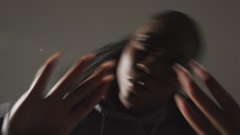 retrato de estudio de una mujer joven con capucha bailando con poca iluminación contra un fondo gris 9
