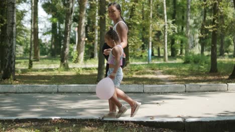 pregnant mother and daughter walking in park with balloon