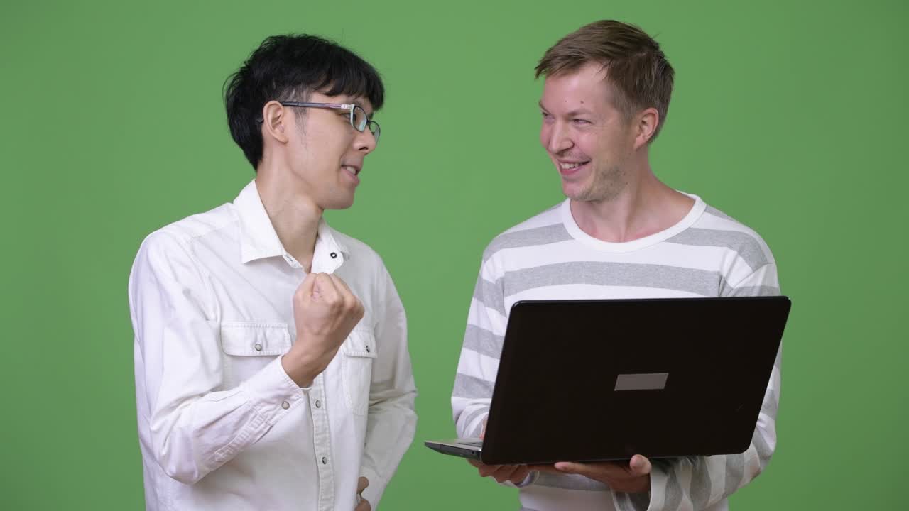 두 명의 행복한 젊은 다민족 사업가들이 함께 좋은 소식을 듣는 동안 노트북을 사용합니다.