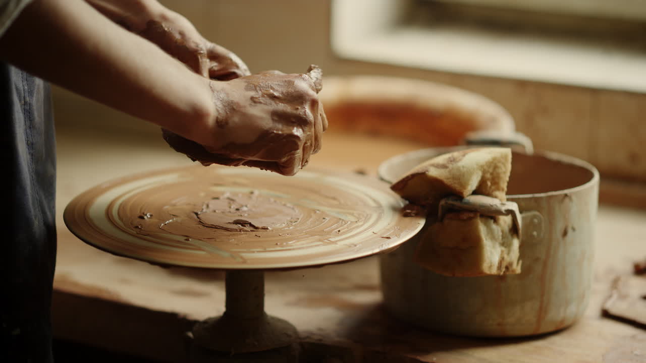Signora sconosciuta che si prepara a creare un prodotto in un laboratorio di ceramica. Mani che modellano l'argilla