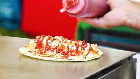 sauce being added to a kebab wrap