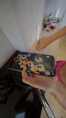 person filming shrimp cooking on a stove with a smartphone