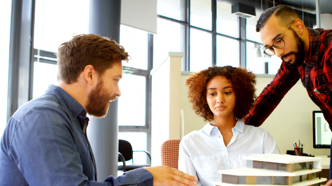 Arquitetos discutindo sobre maquete de construção na mesa 4K