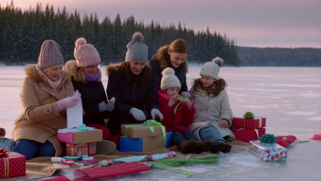 family wrapping christmas gifts by the lake in winter