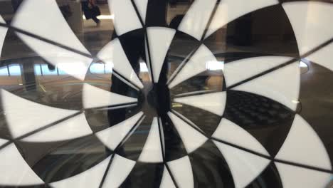 black and white hypnosis spiral moving clockwise on the interior wall with reflection at terminal 3 of san francisco international airport in california