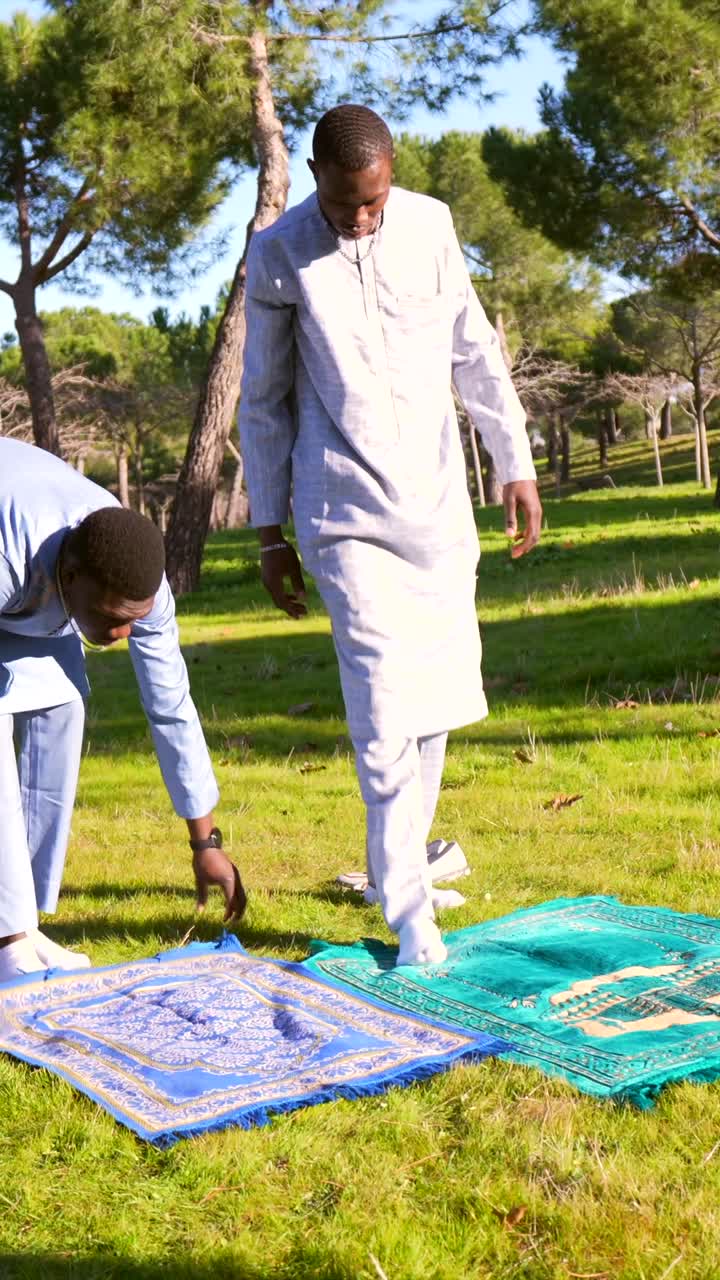 Muslim men setting up prayer rugs in a park