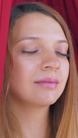 concentrated pretty woman sits relaxed in fly yoga hammock and meditates after workout extreme close view