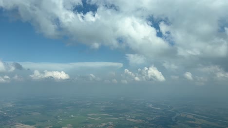 aerial cockpit view, pilot pov, from a jet cockpit during a left turn near milan airport, with a partially cloudy sky and deep blue heaven