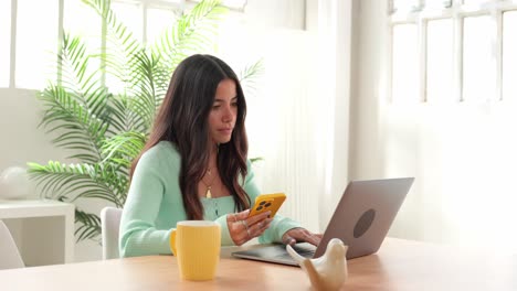 woman using laptop and phone at desk