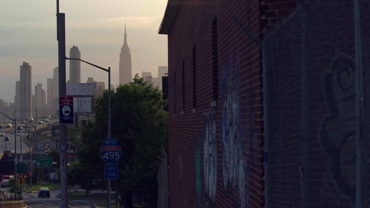 Empire State Building And Highway With Graffitied Brick Building In Foreground In NYC