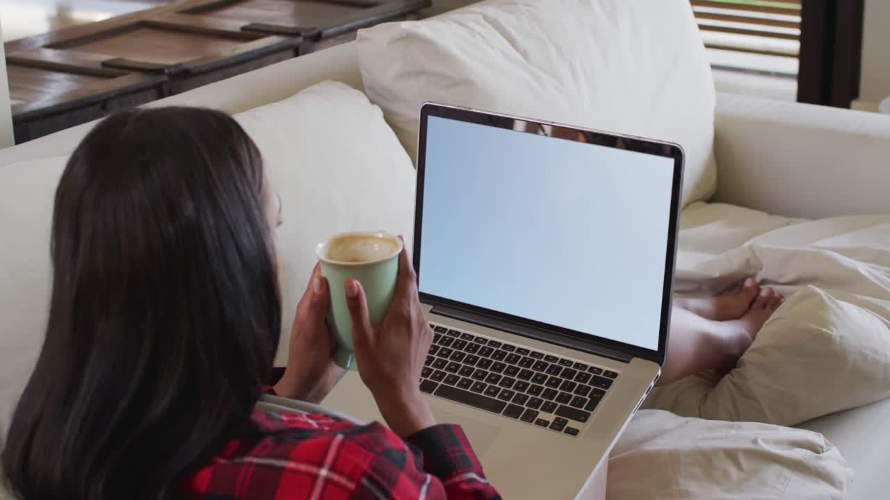 Composizione: donna seduta a casa con un caffè, che guarda una partita di calcio sul laptop.