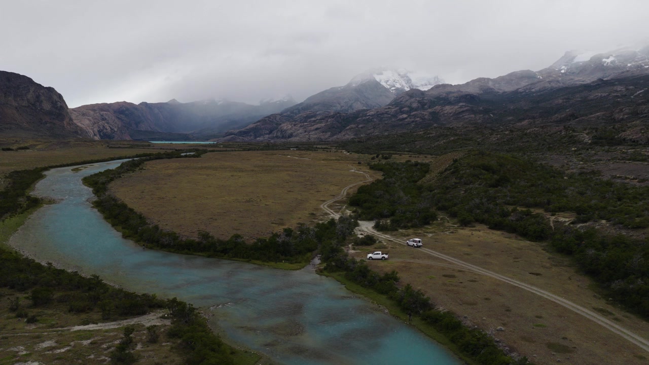 Río de las Vueltas vicino a El Chaltén, Santa Cruz, Argentina, che scorre attraverso valli glaciali sotto il massiccio del Fitz Roy e le Ande meridionali, con steppa patagonica e percorsi terrestri, parallasse drone