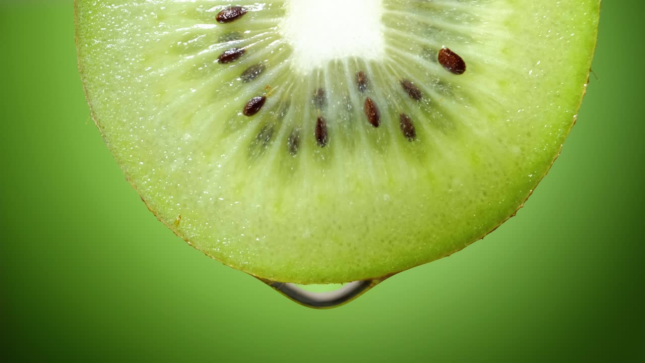 Primer plano o macro de una rodaja de kiwi, una gota de agua cae en cámara lenta
