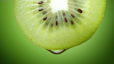 close up or macro of a slice of kiwi, a drop of water falls in slow motion.