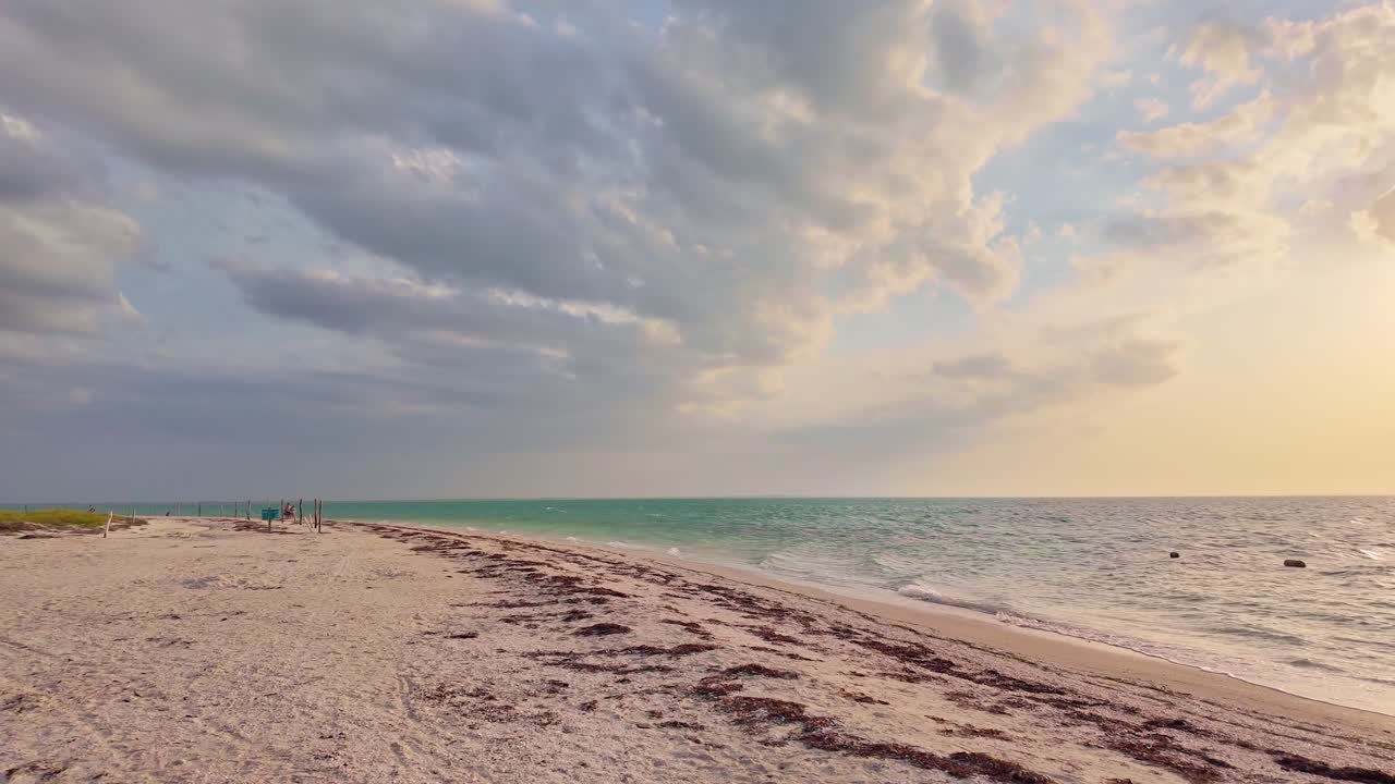Vista della spiaggia all'ora d'oro a Holbox Punta Cocos, Messico, con onde e cielo calmi.