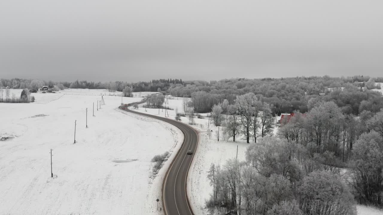 Aerial drone view of a winding highway road in countryside landscape. Cars driving in a winter wonderland scenery. Frost on the trees after extreme cold.