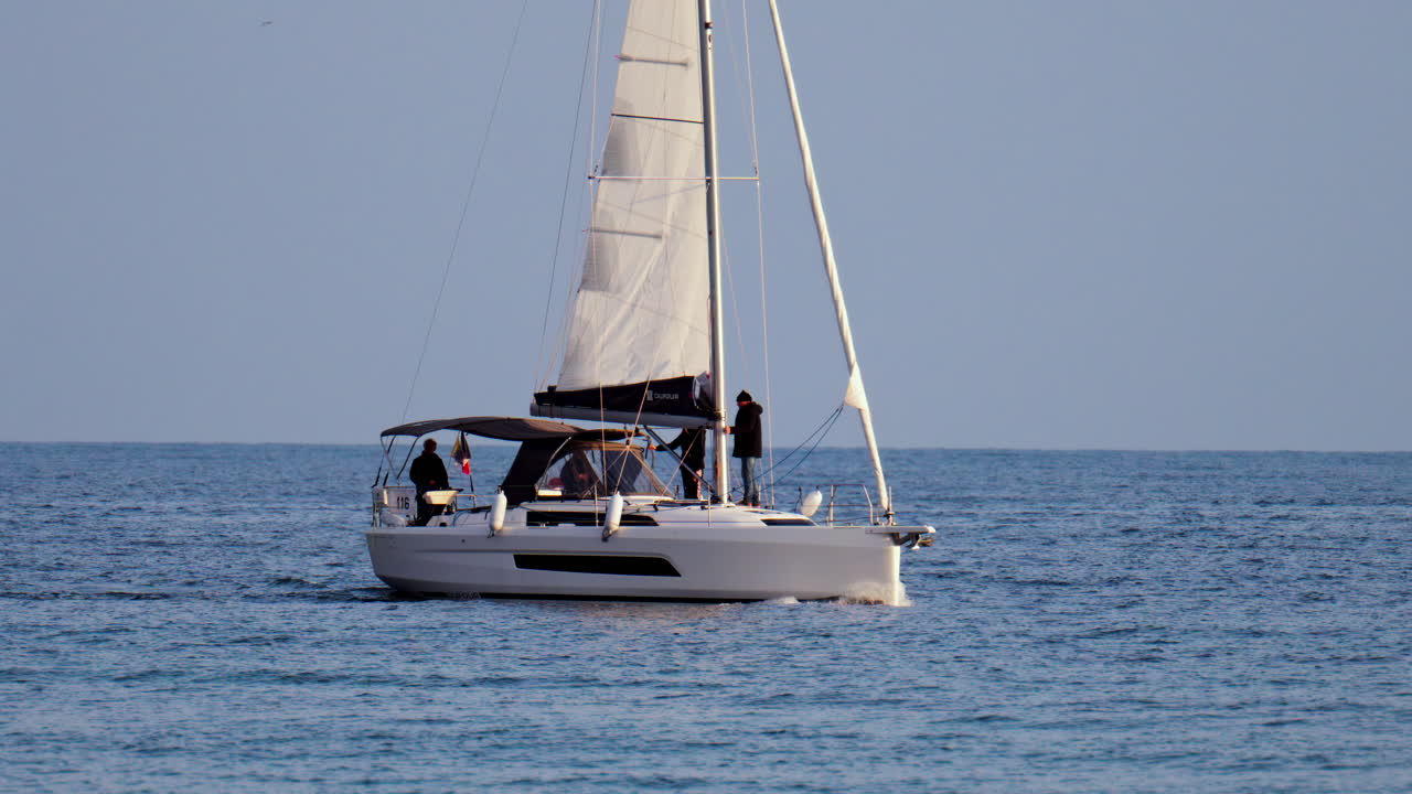 Antibes, France - February 14, 2025: People riding on a sailboat on a cloudy day