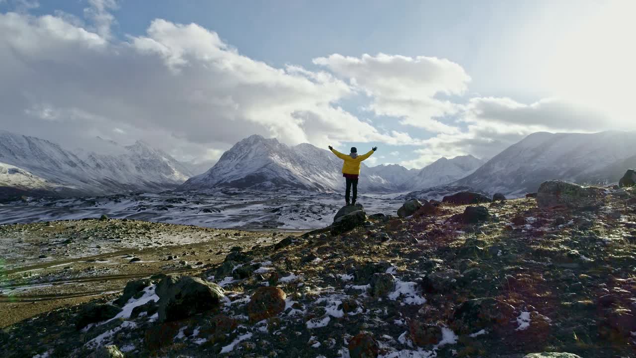 hombre de pie en el pico de la roca invierno nevado cordillera logro éxito brazos extendidos felicidad naturaleza épica belleza vacaciones vacaciones de esquí concepto