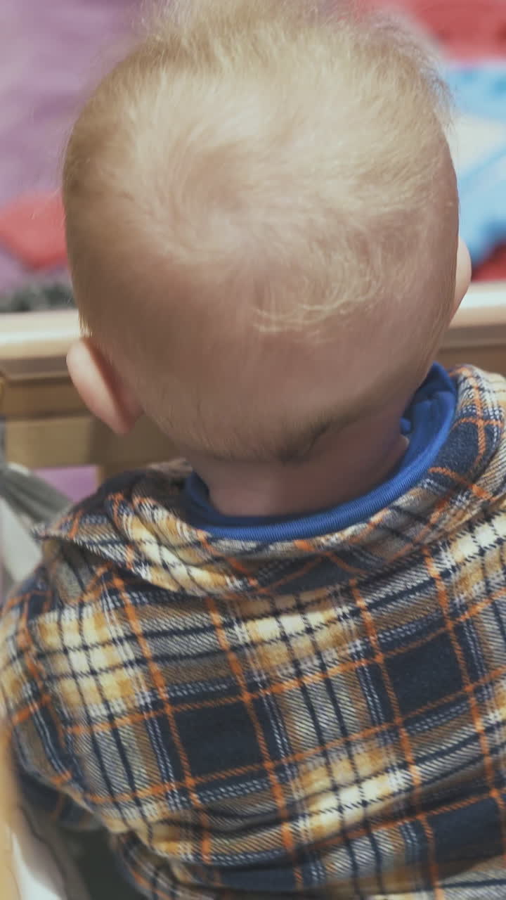 cute little baby in checkered shirt plays in rocking soft cot with star blanket in light room closeup view from above