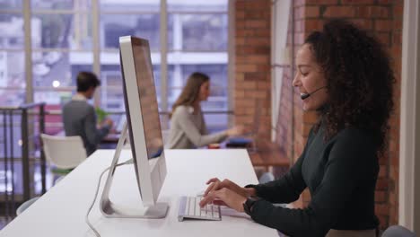 mujer de negocios creativa que usa auriculares hablando en una oficina moderna