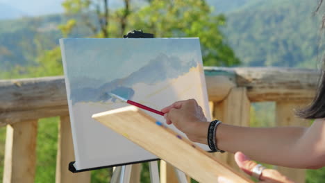 mujer pintando un paisaje de montaña al aire libre