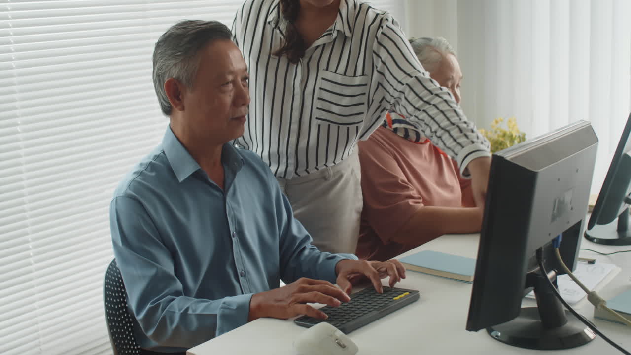 Instructor Helping Mature People with Computers