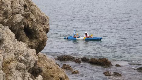 couple kayaking in the ocean by the rocks