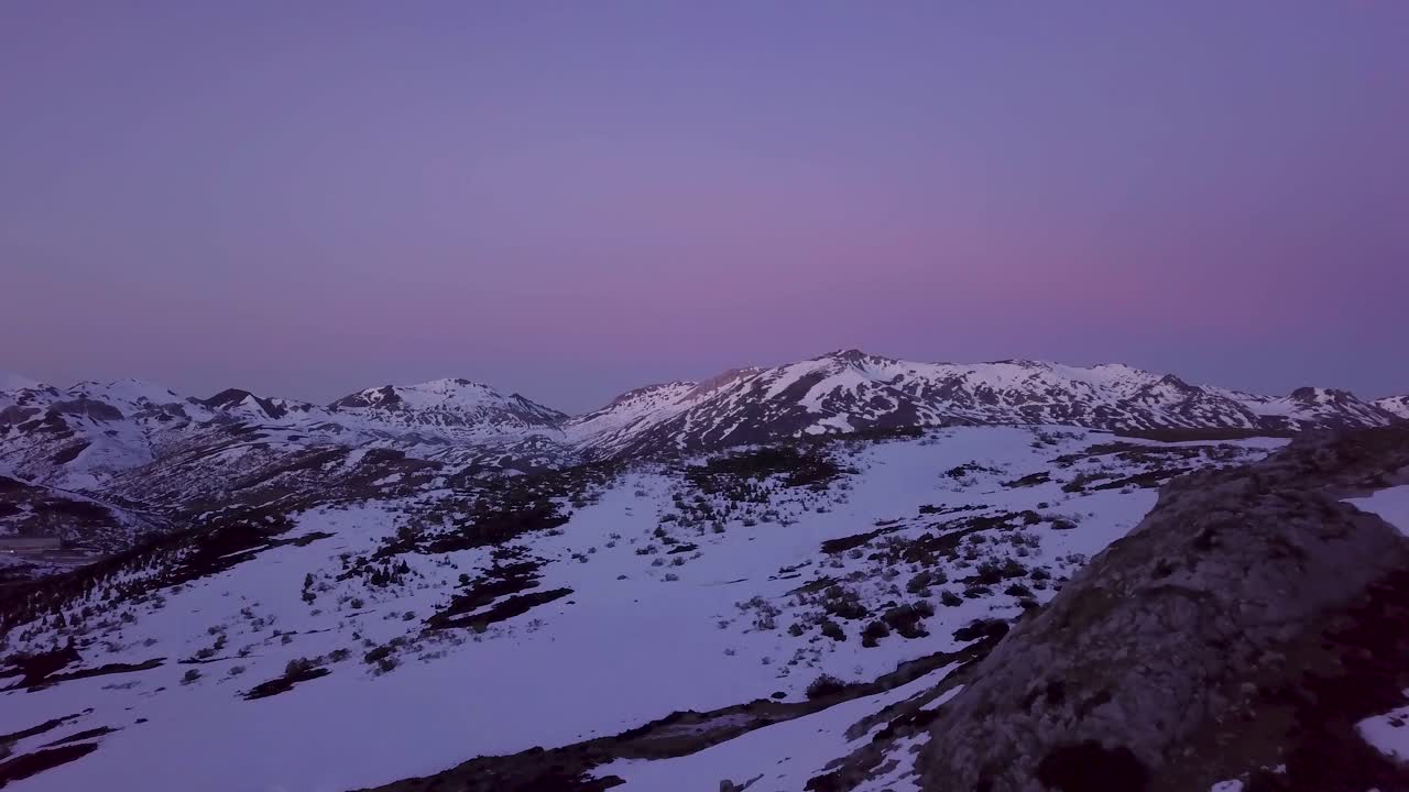 volando sobre las cimas de las montañas cubiertas de nieve en invierno al atardecer