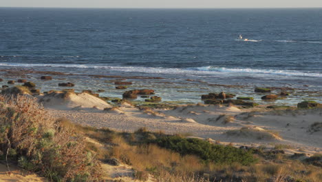 small boat sailing in the background close to the beach