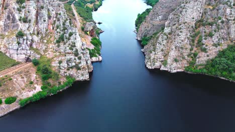 aerial-shot-of-deep-blue-river-flowing-through-steep-valley,-4k