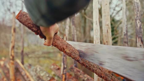 man cutting the wood with a handsaw for skigard wooden fence. - closeup shot