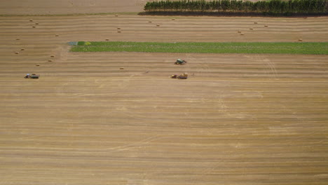 Farmers-at-work-on-hay-field,-harvesting-season-in-USA,-aerial-dolly-in