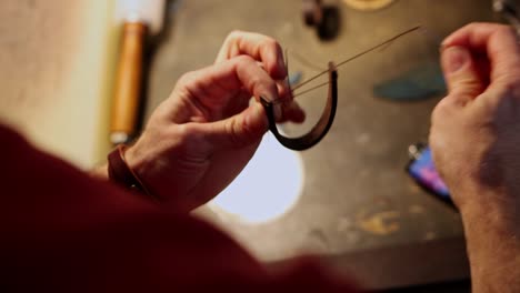 leather workshop - a man sews a belt loop with thick needle