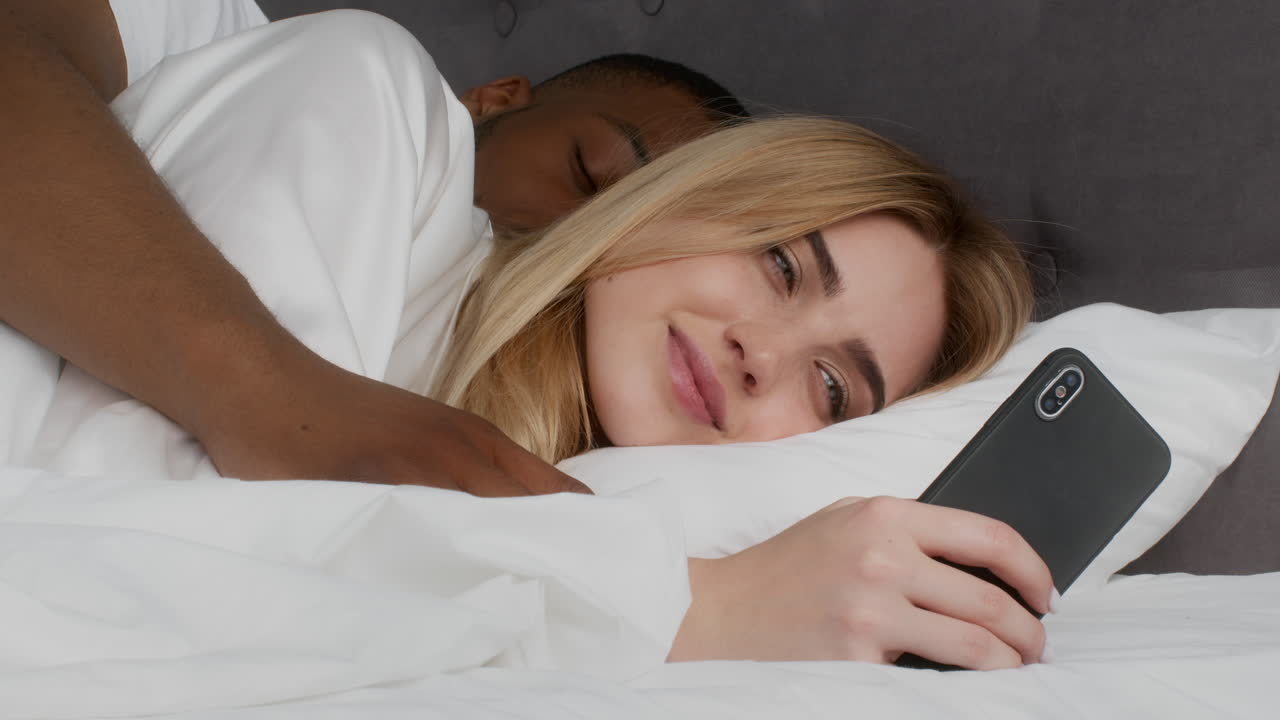 pareja en la cama usando un teléfono inteligente