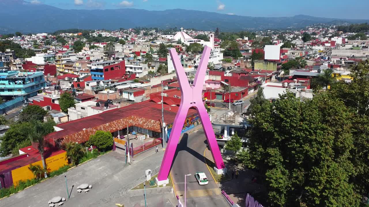 vista aérea de 4k de una enorme x que funciona como un arco para cruzar el icónico puente de xalapa rodeado de naturaleza y casas residenciales de xalapa, veracruz durante el día