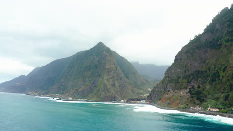 Wunderschöne-Bewölkte-Küstenlandschaft-Madeiras-Mit-Wellen,-Panoramahimmel,-Meer,-Strand-Und-Bergen,-Drohnenaufnahme