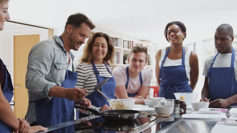 Profesor-Haciendo-Pan-Plano-En-La-Cocina-En-Clase-De-Cocina-Mientras-Los-Estudiantes-Adultos-Miran