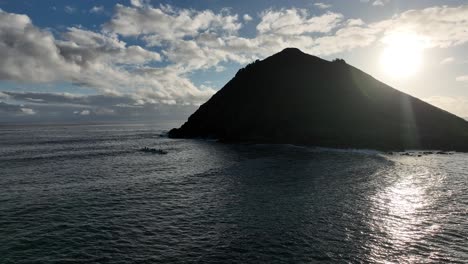 aerial-panning-of-mokulua-islands-in-lanikai-hawaii-at-sunrise-with-clear-beautiful-ocean-water-and-paddlers-in-hawaiian-canoes