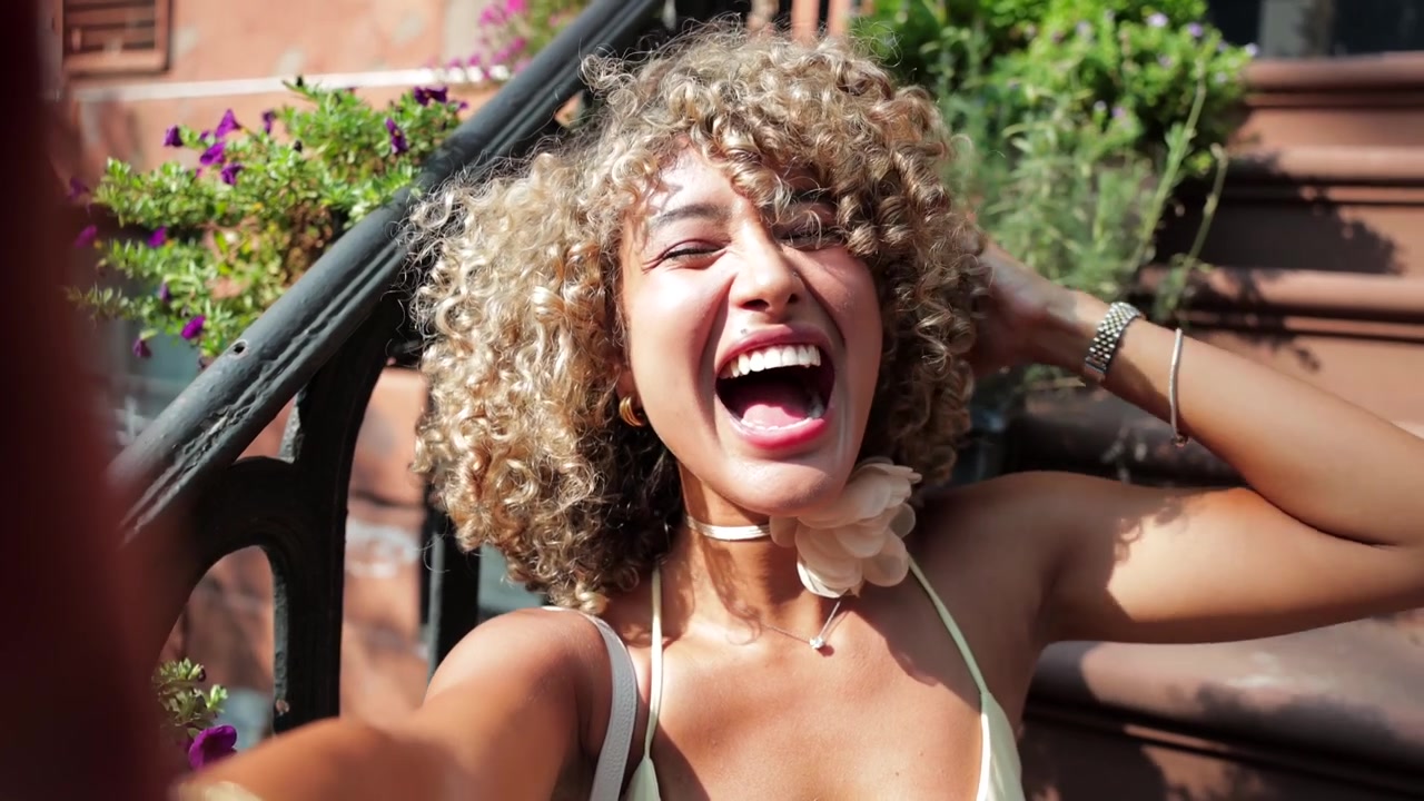 Jeune femme prenant des selfies sur les marches urbaines d'un immeuble en grès brun.