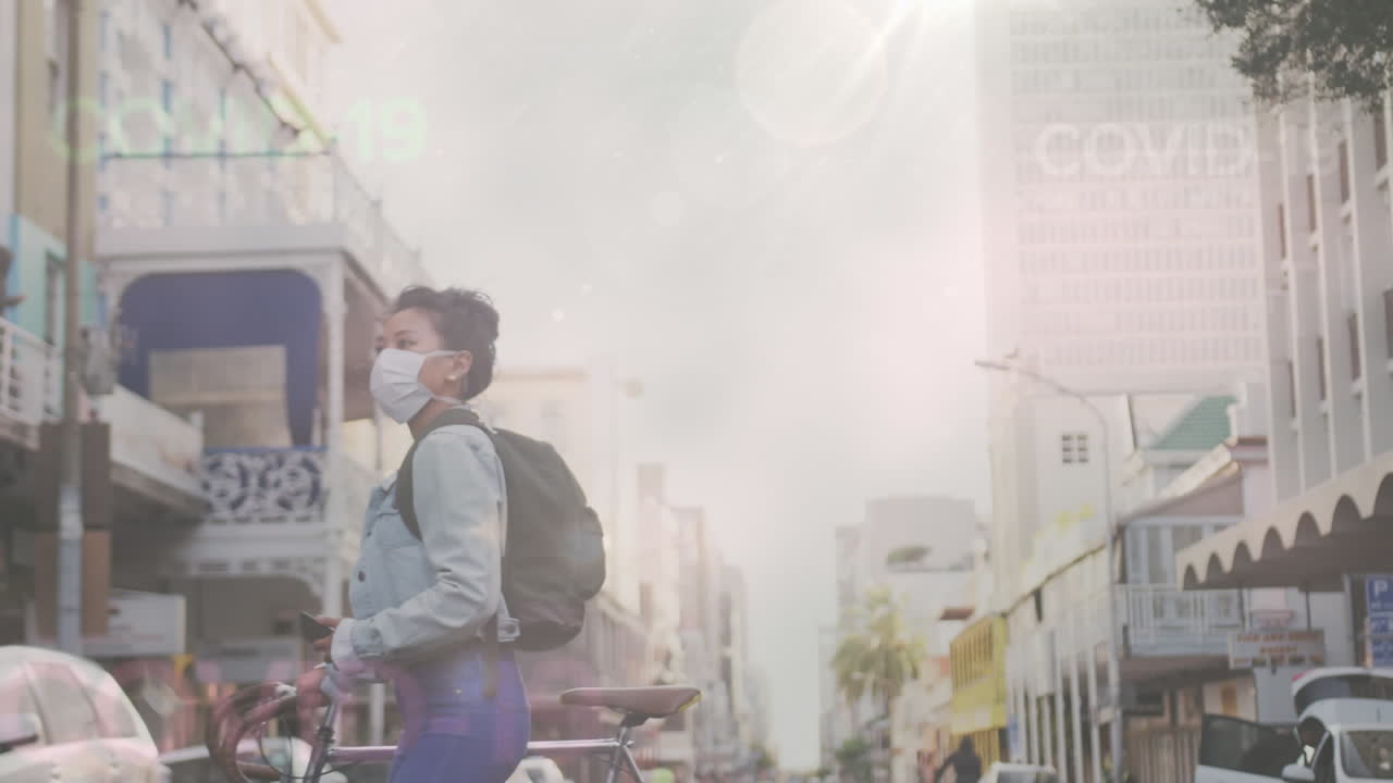 Animasi tulisan Covid-19 mengambang di atas seorang wanita Asia mengenakan masker di jalan dengan sepeda.