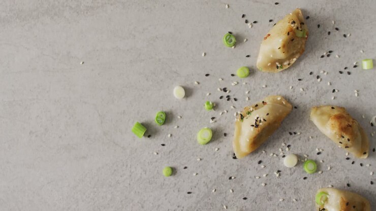 Composition of gyoza dumplings and soy sauce with chopsticks on grey background