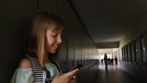 chica usando un teléfono inteligente en el pasillo de la escuela