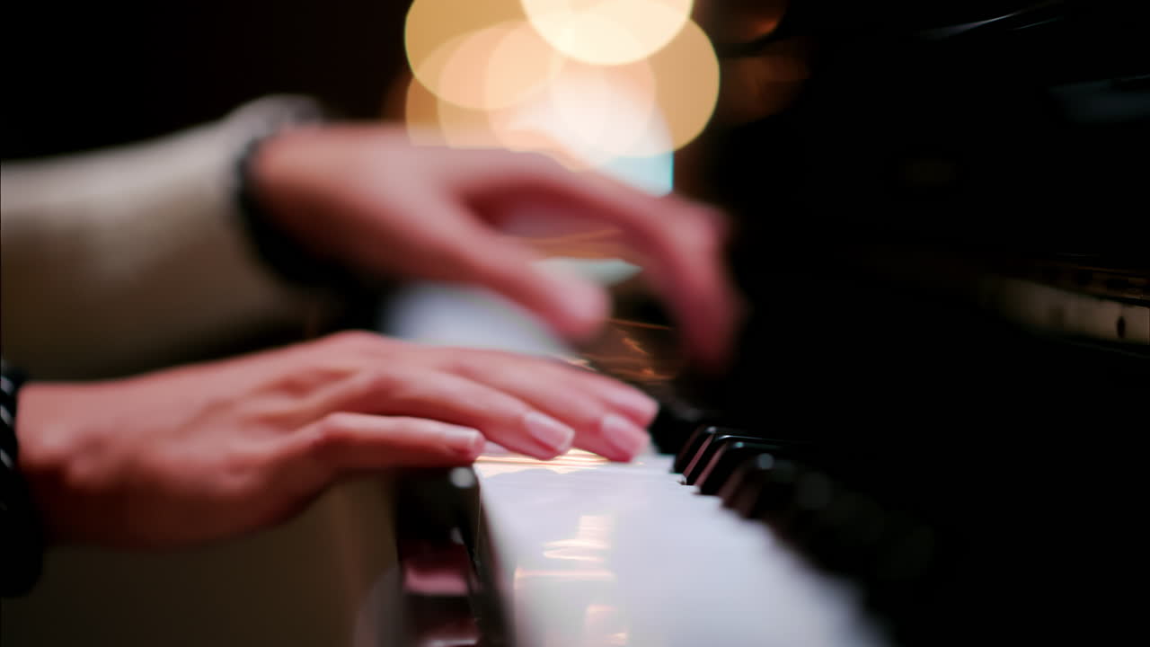 Close up of a woman's hands playing the piano with blurry lights on the background