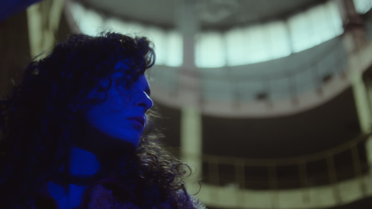 Woman in Blue Neon Light in Dark Building