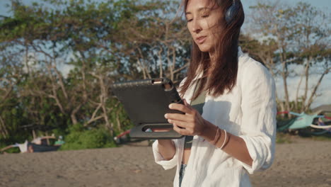 woman with tablet walking on beach