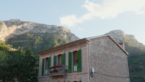 a solitary house nestled in deía, mallorca, spain, with the backdrop of mountains and a blue sky, encapsulating the peaceful charm of the locale