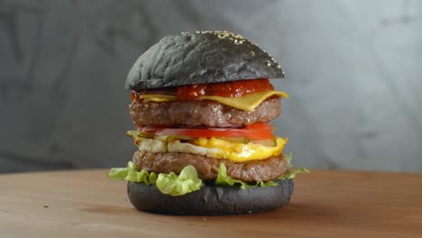 burger or hamburger with black bread on a blurred background of leaves.