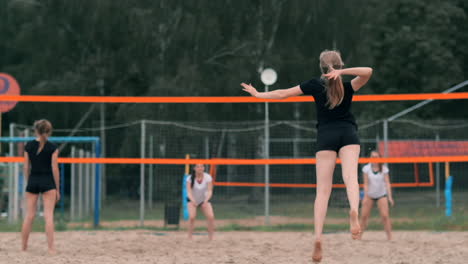 women competing in a professional beach volleyball tournament. a defender attempts to stop a shot during the 2 women international professional beach volleyball.